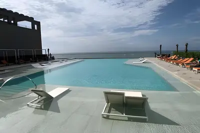 a swimming pool with lounge chairs and the ocean at Espectacular Apto Piso 21 de 2 Hab - Morros City in Cartagena de Indias