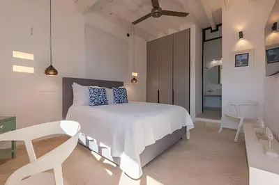a white bedroom with a bed and a chair at El Mirador de la Catedral - Centro Histórico in Cartagena de Indias