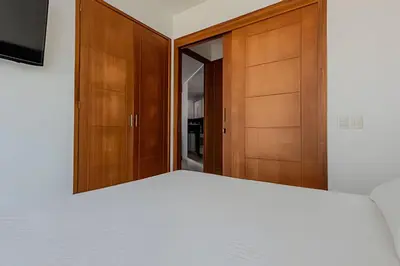 a bedroom with a white bed and wooden cabinets at Espectacular Vista Al Mar - Ed. Infinito 2302 in Cartagena de Indias