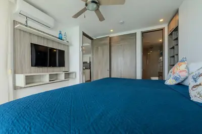 a bedroom with a blue bed and a flat screen tv at Piso 27 - Espectacular apartamento en Bocagrande in Cartagena de Indias