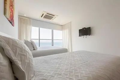 a white bedroom with two beds and a television at 3605 Morros City - Paraiso en Cartagena in Cartagena de Indias