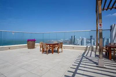 a patio with a table and chairs on a roof at Lujoso Apto Vista al Mar Piso 34 - Palmetto Beach in Cartagena de Indias