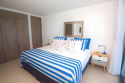 a bedroom with a bed with a blue and white striped blanket at Morros City - Lujoso Apto con vista al mar Piso 28 in Cartagena de Indias