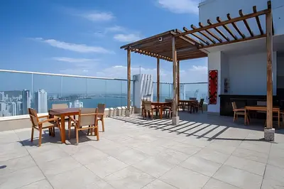 a patio with tables and chairs on a roof at Espectacular apt en el piso 29 en Palmetto Beach in Cartagena de Indias