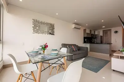 a dining room and living room with a glass table and white chairs at Palmetto Sunset piso 33 - Vista espectacular in Cartagena de Indias