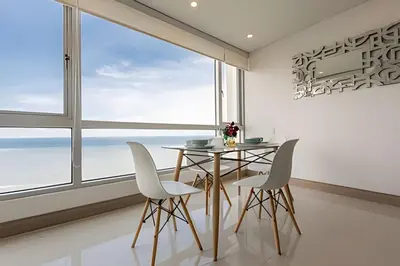 a dining room with a table and chairs and a large window at Palmetto Sunset piso 33 - Vista espectacular in Cartagena de Indias