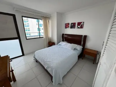 a white bedroom with a bed and a window at Apartamento en Bocagrande con vista lateral al mar ICDI in Cartagena de Indias