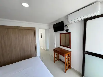 a bedroom with a bed and a desk and a television at Apartamento en Bocagrande con vista lateral al mar ICDI in Cartagena de Indias