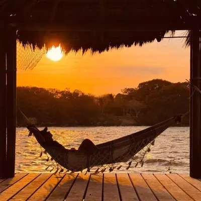 a person laying in a hammock on a dock at Ecohotel Nativa Beach in Cartagena de Indias