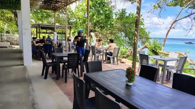 a man standing at a restaurant with tables and chairs at Ecohotel Nativa Beach in Cartagena de Indias