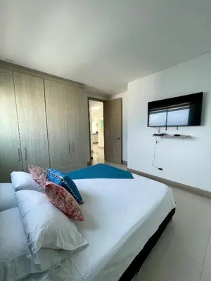 a bedroom with a white bed with pillows and a flat screen tv at Apartamento en Cartagena cerca al Hotel Hilton in Cartagena de Indias