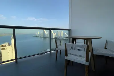 a balcony with a table and chairs and a view of the city at Infinitum Spectacular 23rd floor 1 BR Condo in Cartagena de Indias