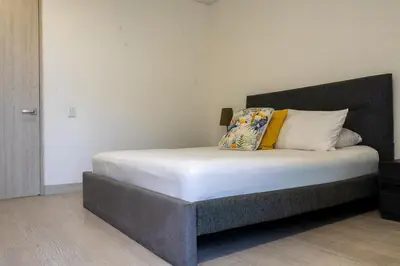 a bedroom with a bed with white sheets and yellow pillows at Modern apt near the beach with Jacuzzi, Cartagena in Cartagena de Indias