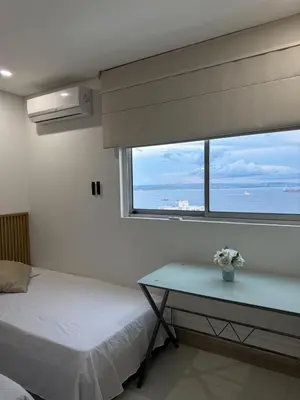 a bedroom with a bed and a table and a window at Apartamento en Palmetto sunset frente al mar piso 20 in Cartagena de Indias