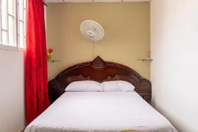 a bedroom with a wooden bed with a red curtain at Donde Mire in Puerto Colombia