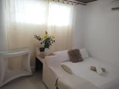 a white bed with a couch and a window at Apartamento en Manga cerca al Centro Historico in Cartagena de Indias