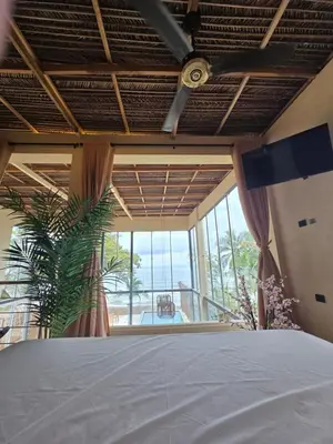 a bedroom with a bed and a large window at Lotus Beach House playa privada in San Silvestre