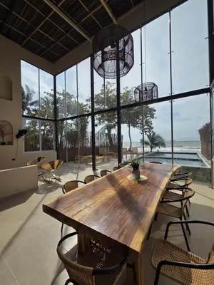 a large wooden table and chairs in a room with windows at Lotus Beach House playa privada in San Silvestre
