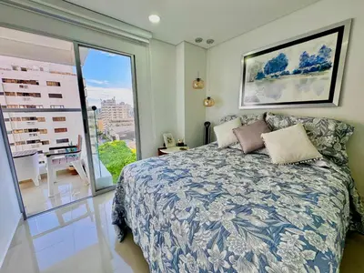 a bedroom with a bed and a large window at Stunning Bocagrande Beach Apartment in Cartagena de Indias