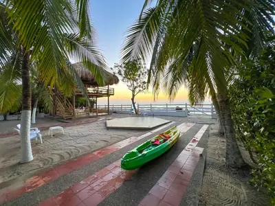 a green canoe parked next to a beach with palm trees at Casa San Miguel Tolú, Playa El Francés in San Silvestre