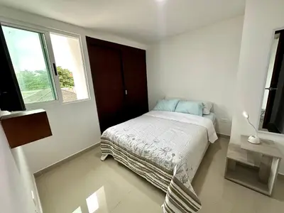 a white bedroom with a bed and a window at Dubai 202 in Barranquilla