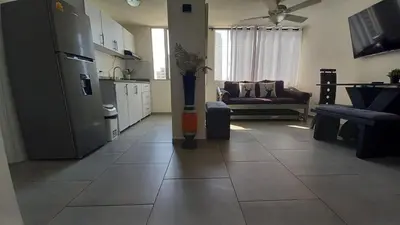 a kitchen with a refrigerator and a living room at Apartamento Cerca a la playa, Piscina, Wifi, AC in Cartagena de Indias