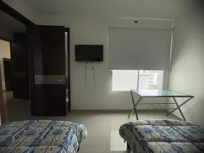 a bedroom with a bed and a table and a window at Bijao 6b in Barranquilla