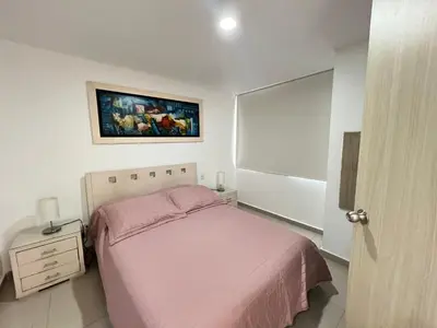 a bedroom with a pink bed and a painting on the wall at Kairos 1209 in Barranquilla