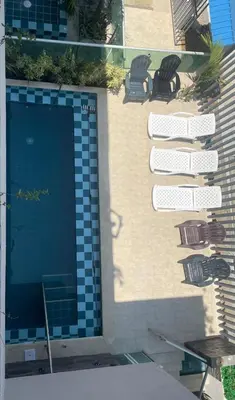 a swimming pool with two chairs and a building at Apartaestudio Terraza del Sol 101 in Coveñas