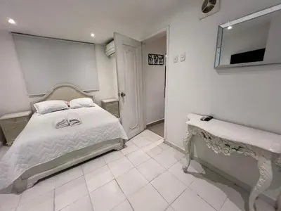 a white bedroom with a bed and a mirror at Edificio Quintero in Barranquilla