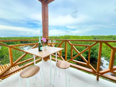 a table with two chairs and a bottle of wine on a balcony at Apartamento frente al mar in San Silvestre