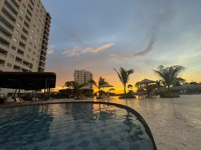 a swimming pool with a sunset in the background at Apartamento cerca del mar- SantaMarina-604 in Santa Marta