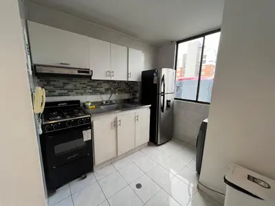 a kitchen with a black refrigerator and white cabinets at Vistas del Mar in Barranquilla