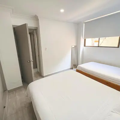 two beds in a white room with a window at Riomar in Barranquilla