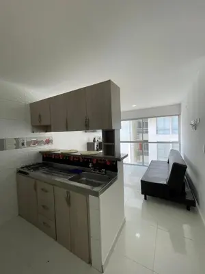 a kitchen with a stove and a couch in a room at Apto Amplio con Piscina 3 Hab a Pasos del Mar in Cartagena de Indias
