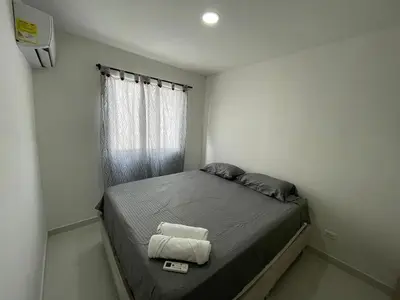 a small bedroom with a bed with two towels on it at Apto Amplio con Piscina 3 Hab a Pasos del Mar in Cartagena de Indias