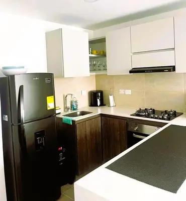a kitchen with a black refrigerator and wooden cabinets at New and Modern Loft in exclusive northern area in Barranquilla