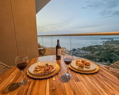 a table with two glasses of wine and food on it at Apartment on the 21st floor, ocean and Sierra views in Simón Bolivar