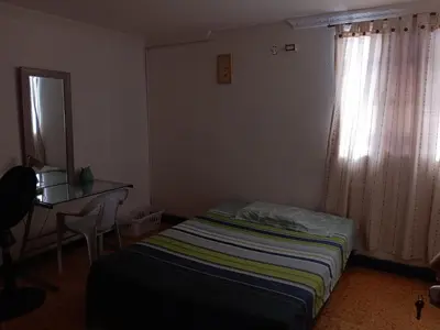 a bedroom with a bed and a desk and a window at Hostal Mr Key in Barranquilla