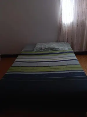 a bed with a striped mattress in a room at Hostal Mr Key in Barranquilla