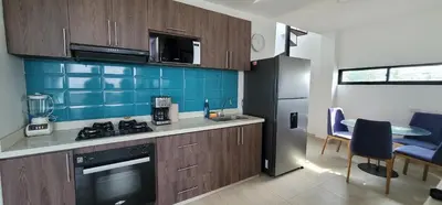 a kitchen with brown cabinets and a blue tiled wall at Live Stay - Boquilla SunSet in Cartagena de Indias