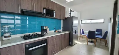 a kitchen with wooden cabinets and a table with chairs at Live Stay - Boquilla SunSet in Cartagena de Indias