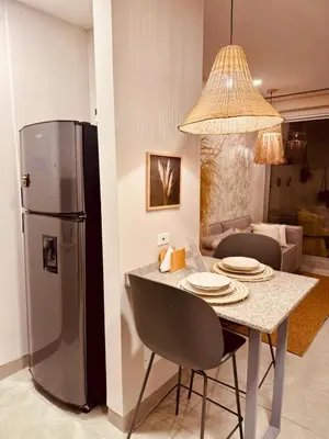 a kitchen with a table and a refrigerator at Apartamento Bohemio frente al Mar en Santa Marta in Santa Marta