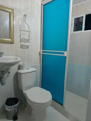 a bathroom with a toilet and a blue shower door at Hospedaje Torices Cartagena in Cartagena de Indias