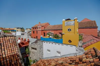 an overhead view of roofs with a clock tower at Casa Stella - Authentic Luxury Rooftop Pool in Cartagena de Indias