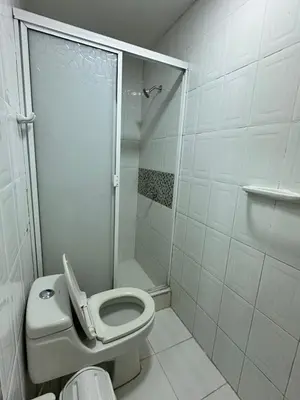 a white bathroom with a toilet and a shower at Hotel H&H in Cartagena de Indias