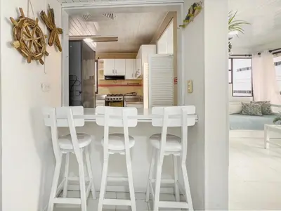 a kitchen and living room with a white counter and stools at Tropical Beach - Con vista al mar in Cartagena de Indias