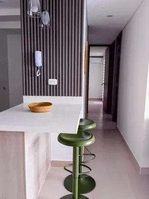 a kitchen with a counter with two green stools at Apartamento moderno cerca de la playa in Cartagena de Indias