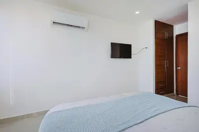 a white bedroom with a bed and a television on the wall at Riviera Suite - Apartamento con balcón in Cartagena de Indias