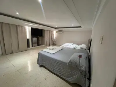 a white bedroom with two beds and a television at Casa Mansion in Barranquilla